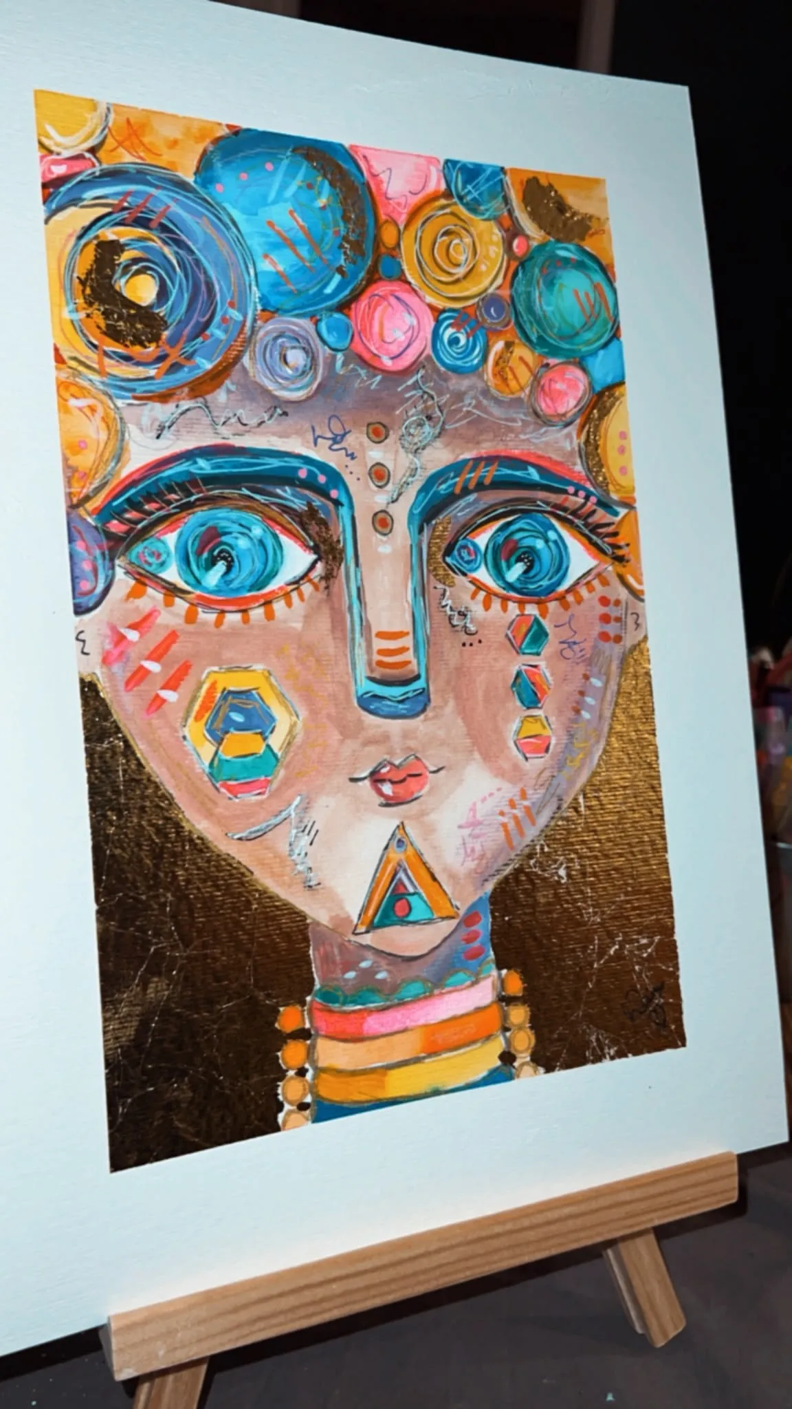 Painted face with gold leaf background on an easel