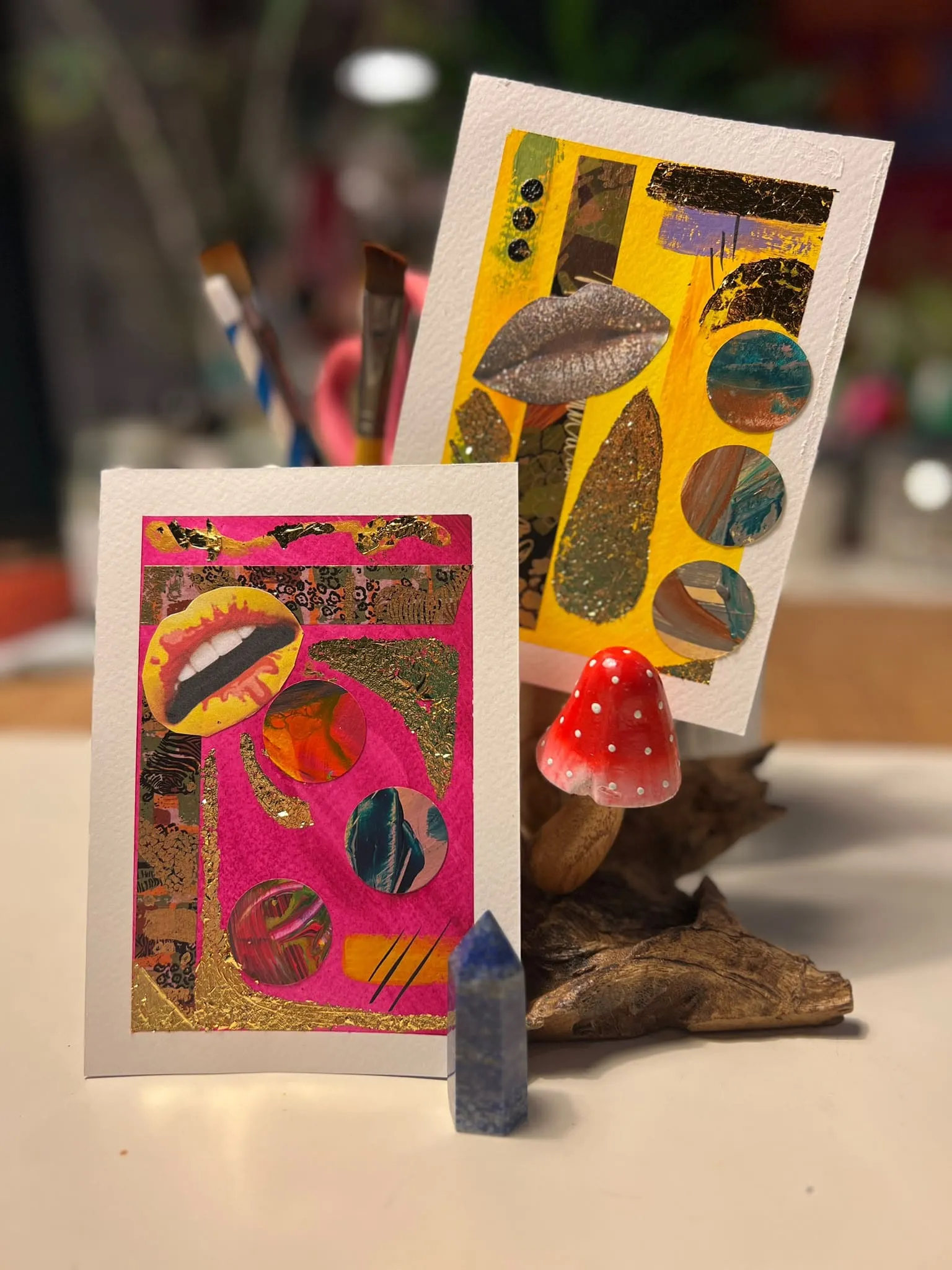 Gold and pink lips collage cards beside a crystal and toadstool