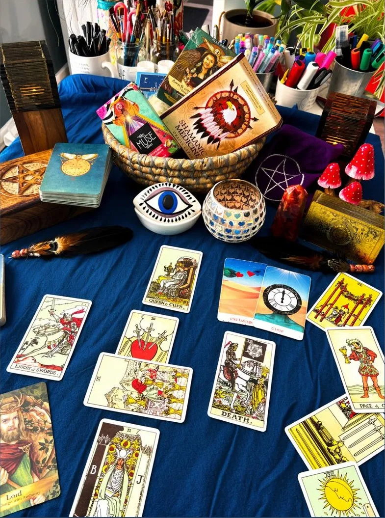 Tarot cards laid out on a blue cloth with crystals and oracle decks